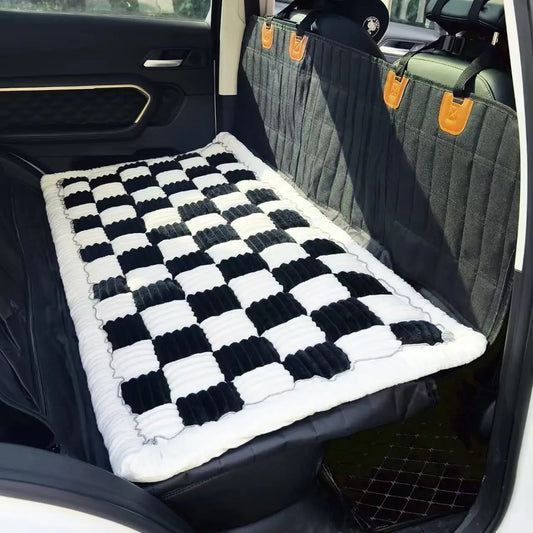 Black-and-white plush dog bed placed across a vehicle back seat